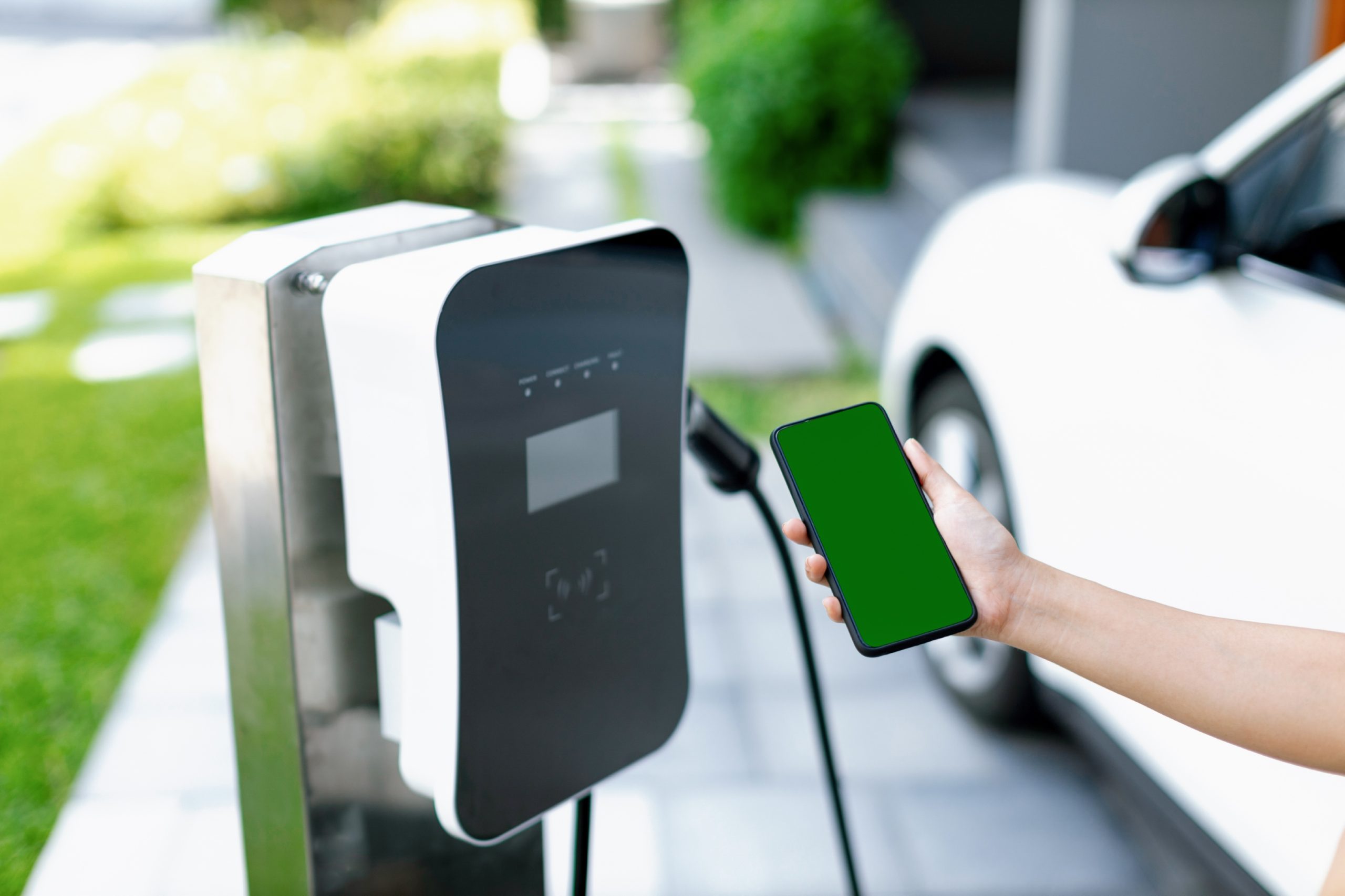 Progressive concept of green screen mockup phone, EV car and charging station.